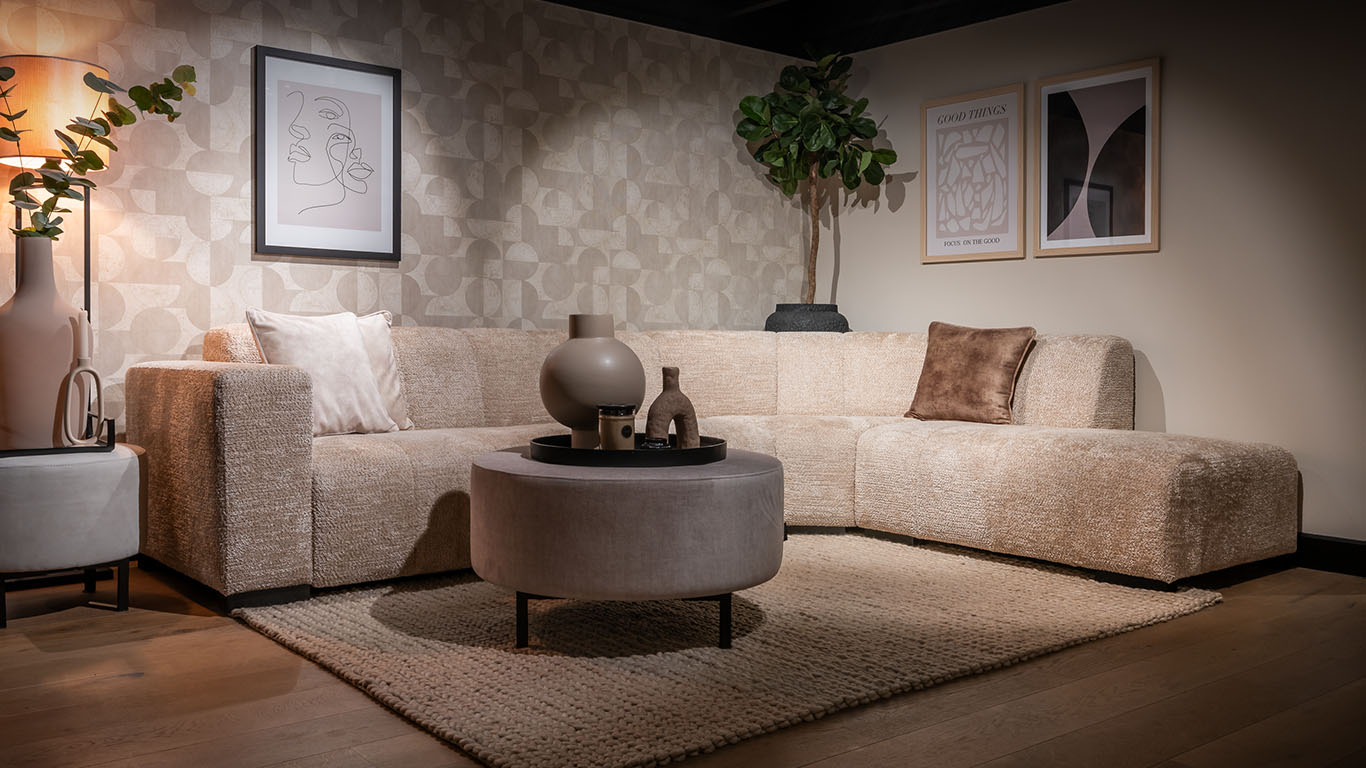 Moderne Pascalle hoekbank in een zachte Fullerton stof in zandkleur, gecombineerd met een elegante Paris Hocker.
