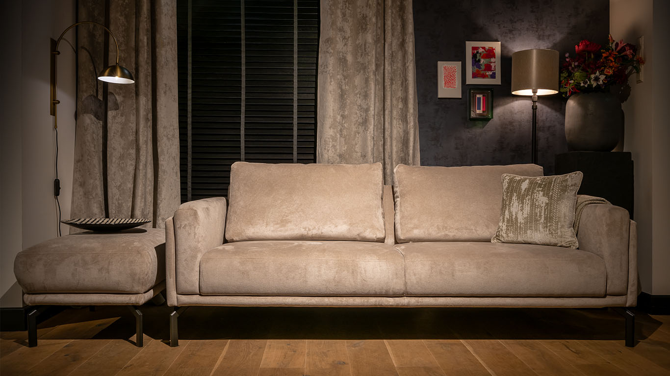 UrbanSofa Vigo Sofa met een Casia rugkussen in de stof Monti Sand, met daarnaast de Vigo Hocker in de stof Monti Sand